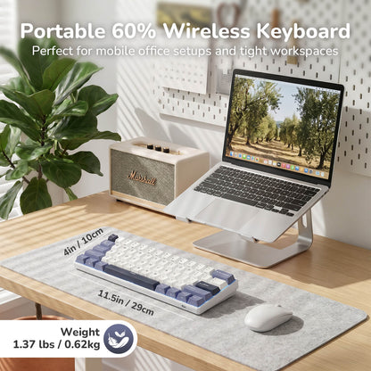 Portable 60% wireless keyboard on a desk with a laptop and plant in the background